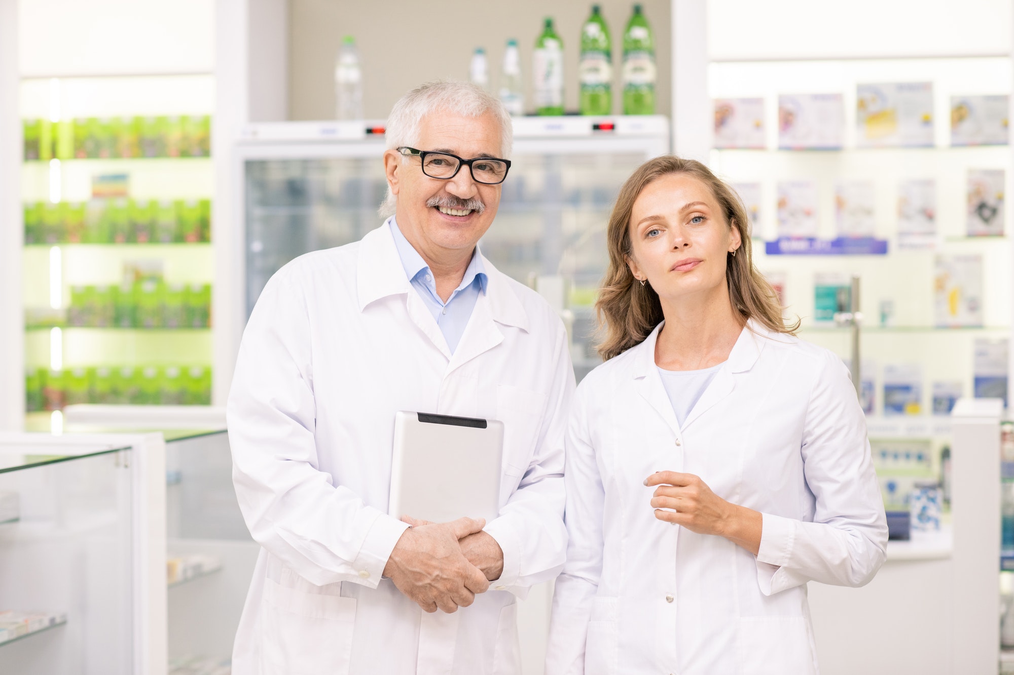 pretty-blond-female-pharmacist-and-her-senior-colleague-in-whitecoats.jpg